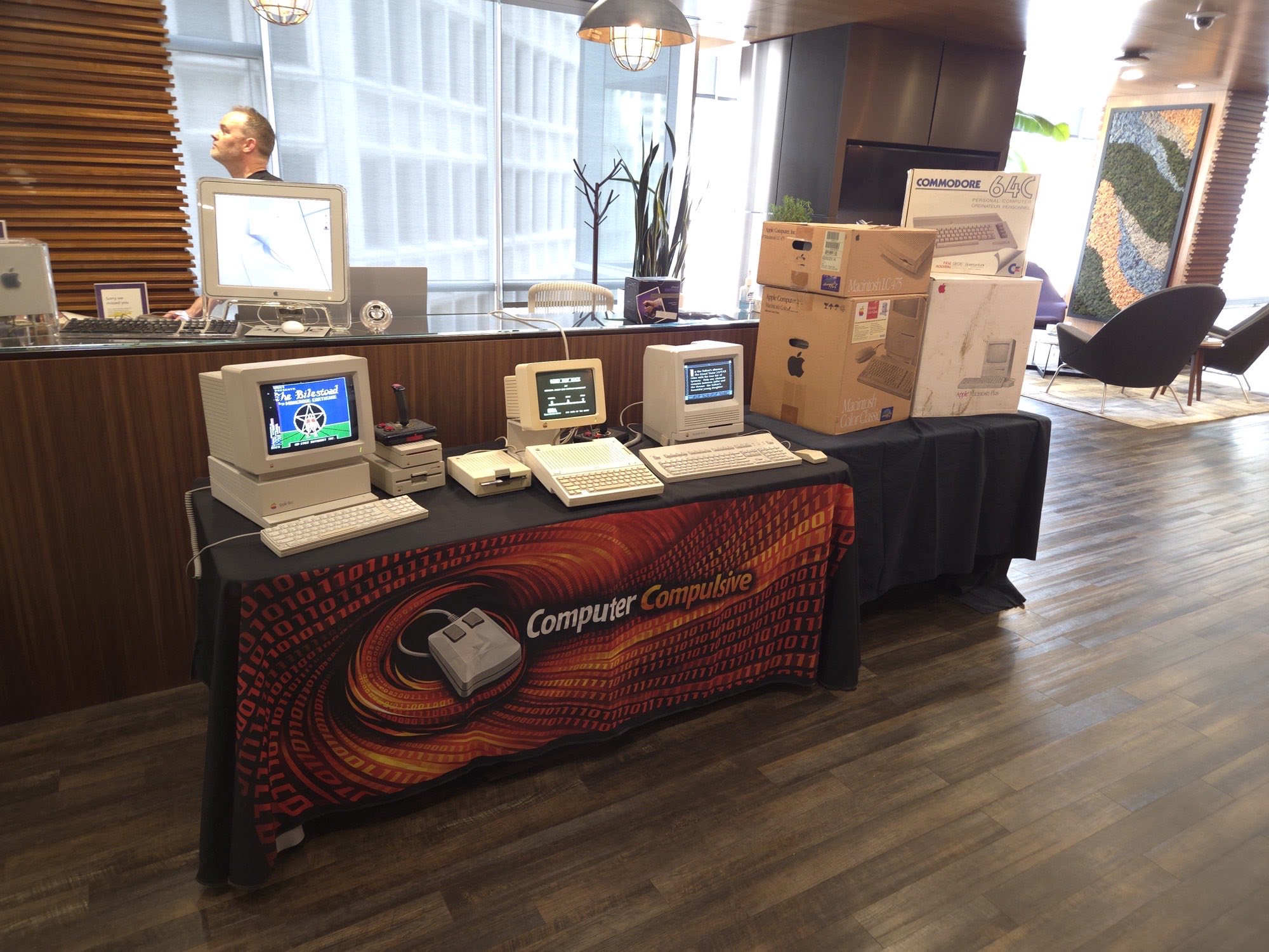 Boxed Commodore 64C beside vintage Apple computers on a display table